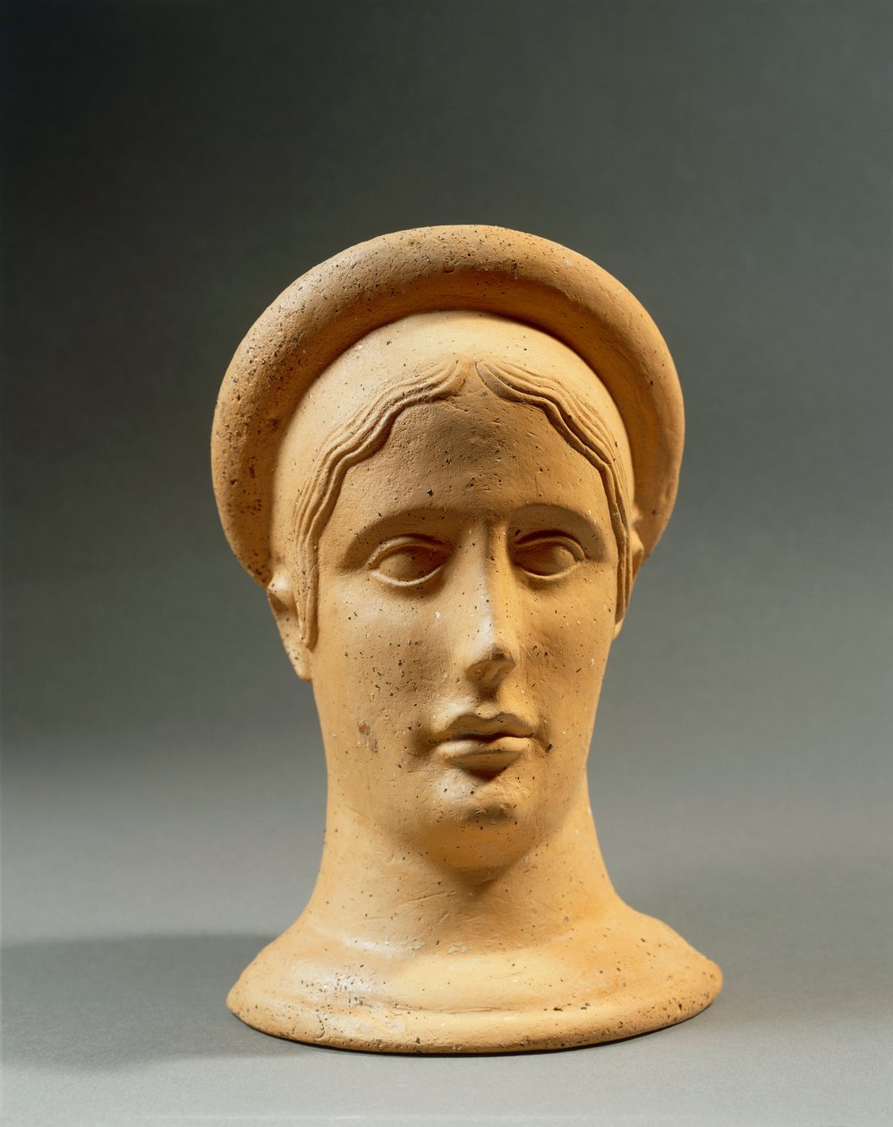 Close-up of a bronze votive feminine head with a cap, Italic civilization, 4th-3rd century b.C. بواسطة الكسندر جبرائيل (بعد) ديكامبس