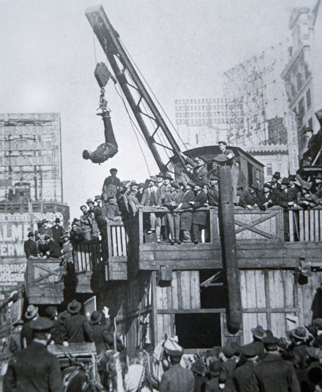 Houdini escaping from a strait-jacket while suspended from a crane in New York City (b/w photo) بواسطة مصور أمريكي