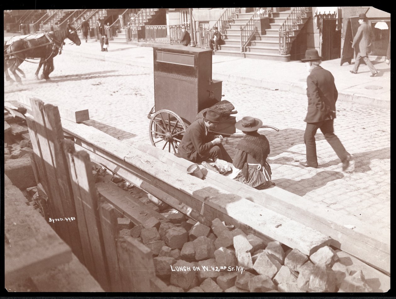 منظر لعضو في الشارع وامرأة تتناول غداء في شارع 42 ستريت الغربي ، نيويورك ، 1898 (طباعة الجيلاتين الفضي) بواسطة شركة بايرون