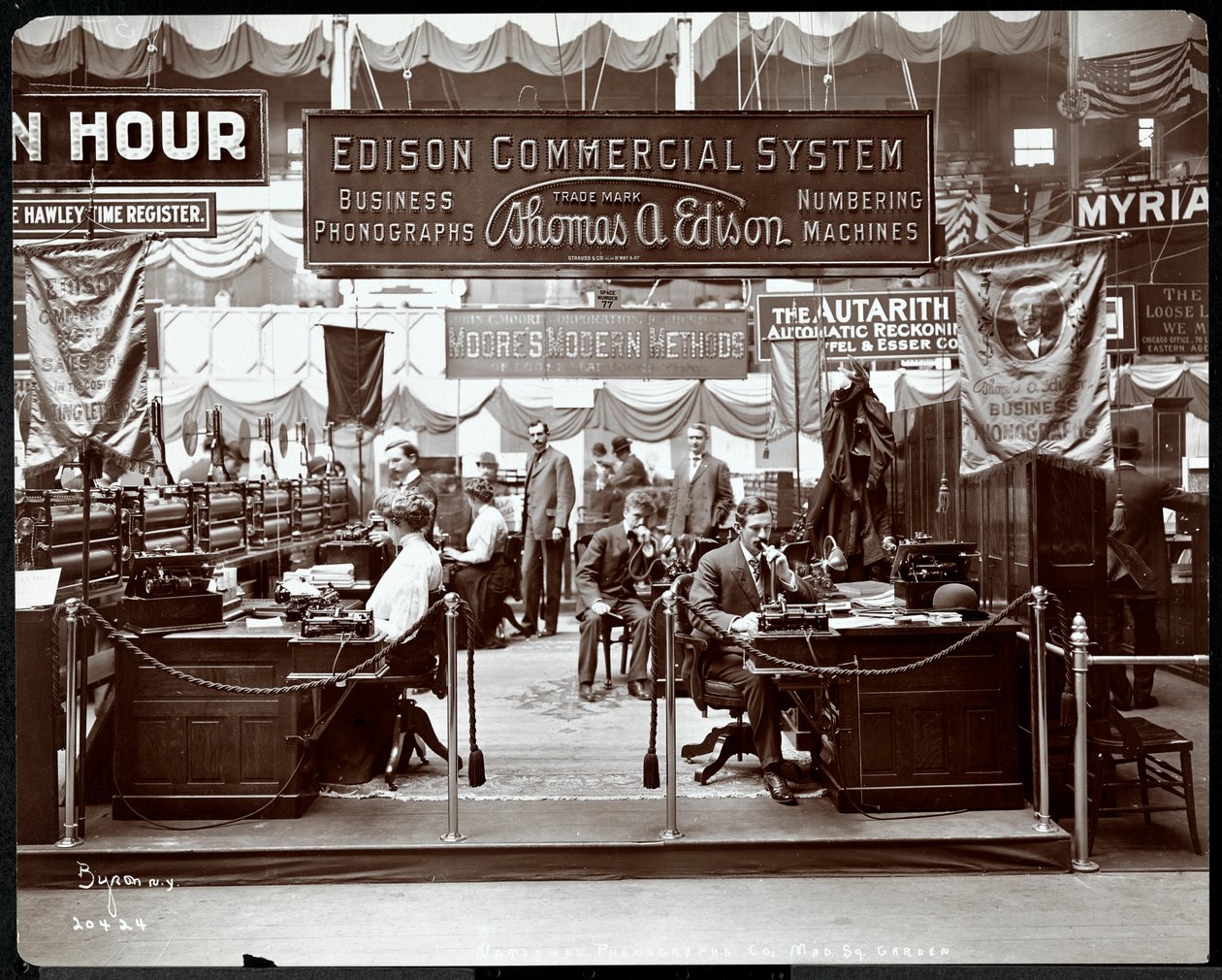 مشهد من كشك شركة Edison Co. لمعدات المكاتب في معرض تجاري في Madison Square Garden ، نيويورك ، 1905 (طباعة الجيلاتين الفضي) بواسطة شركة بايرون