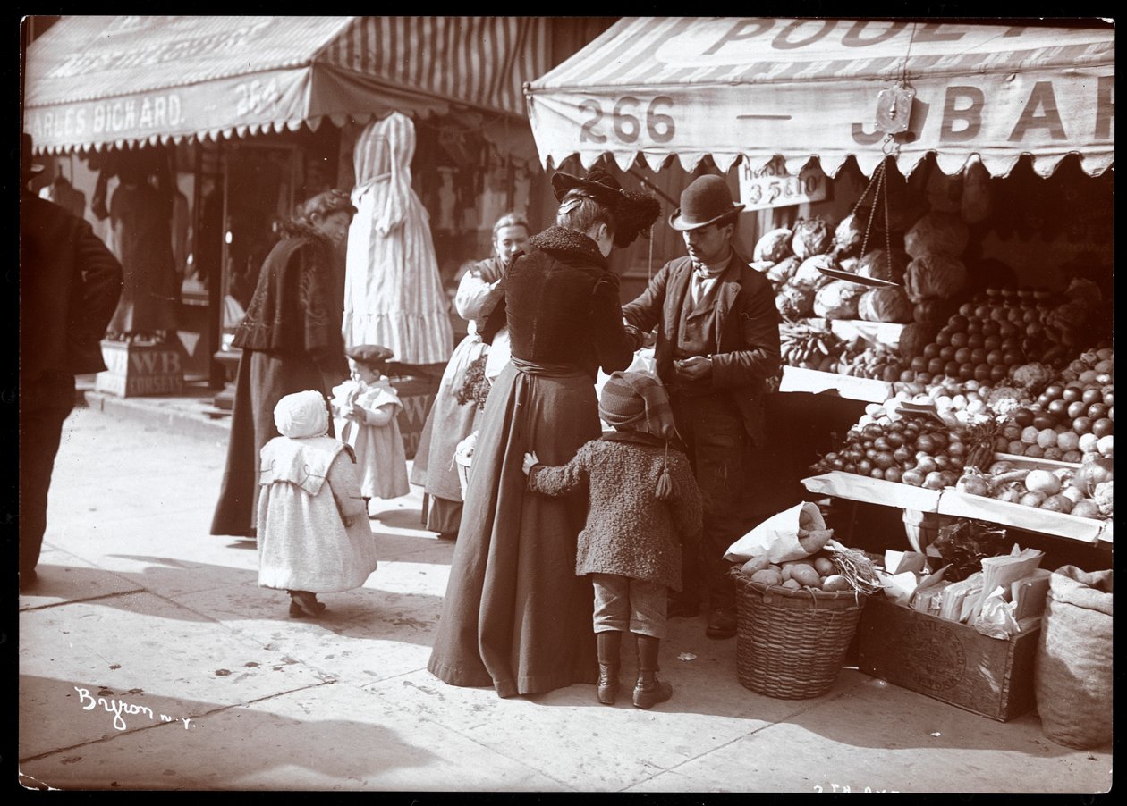 منظر لنساء مع أطفال يتسوقون في موقف الفواكه والخضروات في 266 7th Avenue ، نيويورك ، c.1900 (طباعة الجيلاتين الفضي) بواسطة شركة بايرون