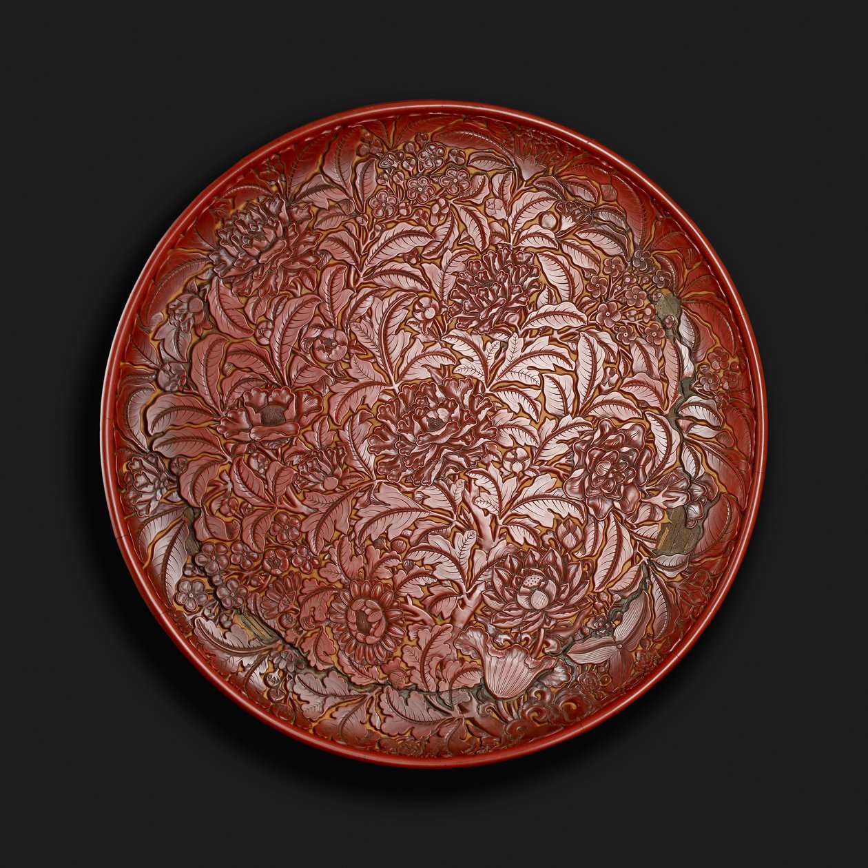طبق منحوت يحمل علامة Xuande (1426-36) في القاعدة ، صيني (طلاء أحمر على الخشب) بواسطة المدرسة الصينية