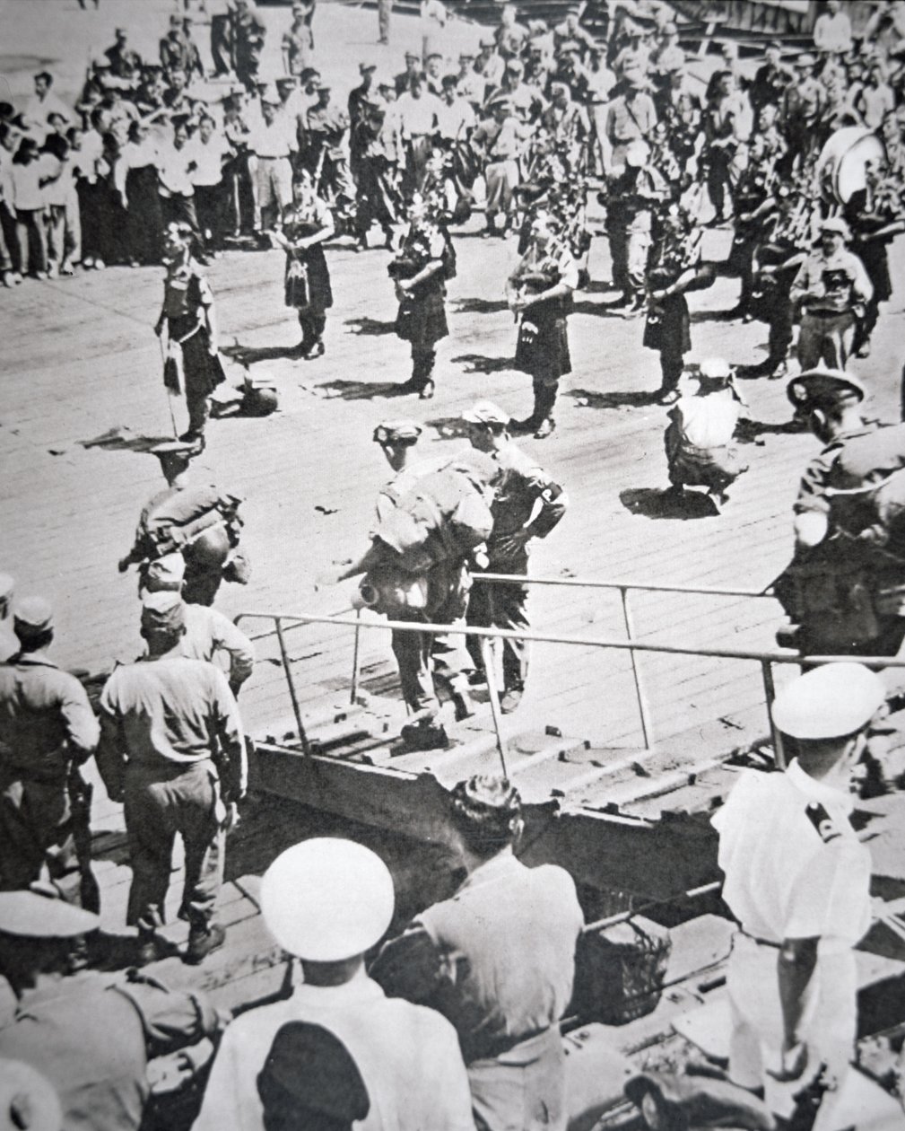 Kilted pipers play ashore from the 1st Battalion Argyll and Sutherland Highlanders from HMS Ceylon at Pusan, 29th August 1950 (b/w photo) بواسطة مصور انجليزى