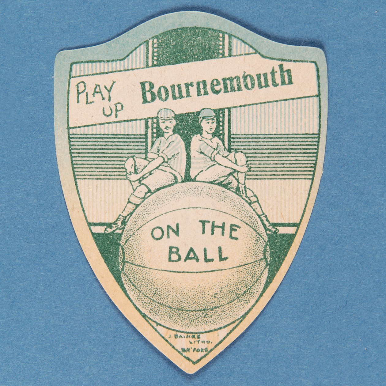 Play Up Bournemouth ، بطاقة Baines على شكل درع واثنين من لاعبي كرة القدم يجلسون فوق كرة قدم كبيرة ، 1888-1889 بواسطة مدرسة اللغة الإنجليزية