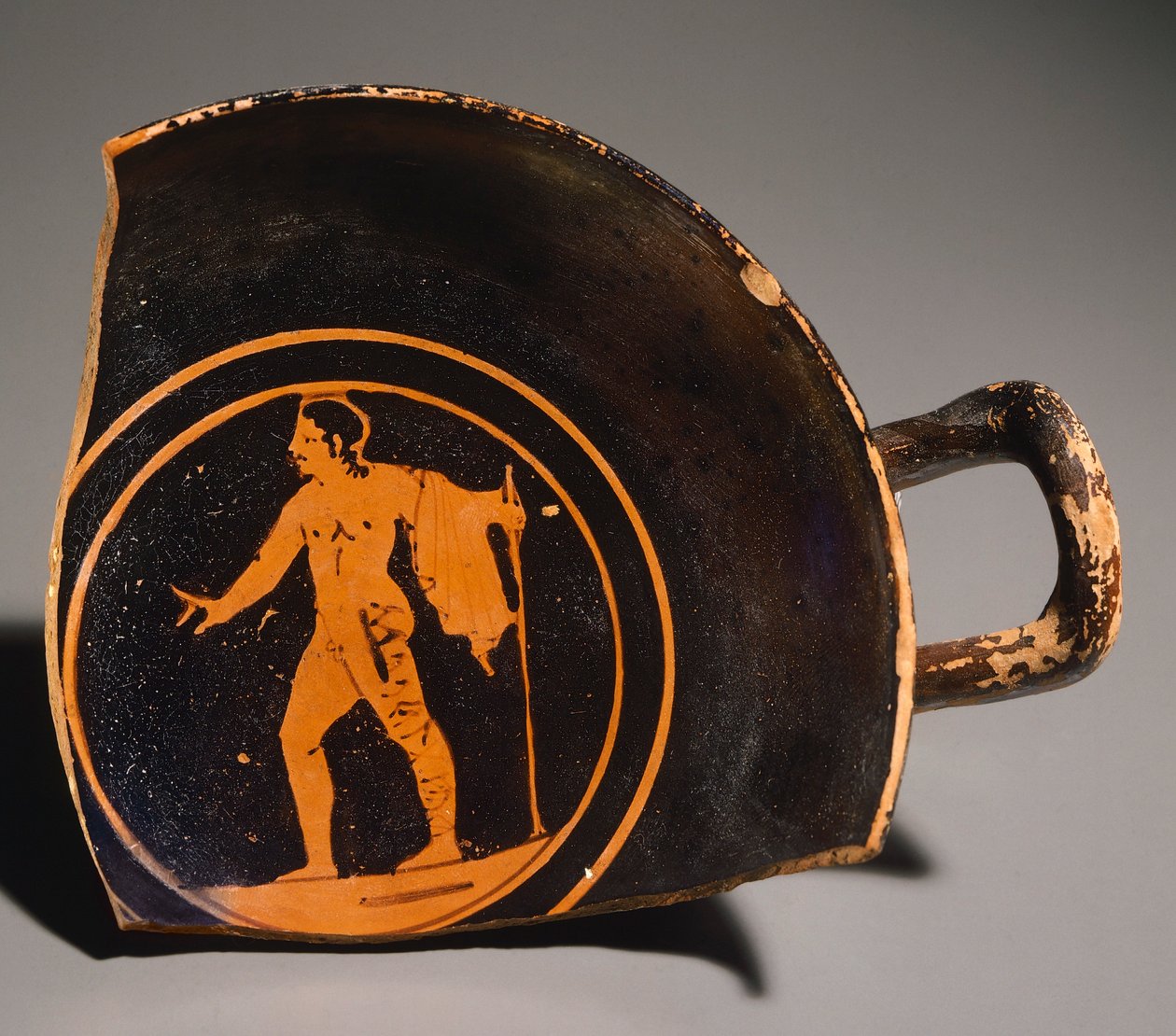 Kylix بواسطة Pteriu Paves ، جزء يصور شابًا ونقشًا. فخار أحمر الشكل ، من القبر 3 في جروتي (توسكانا). الحضارة الأترورية ، القرن الرابع قبل الميلاد. بواسطة إتروسكان