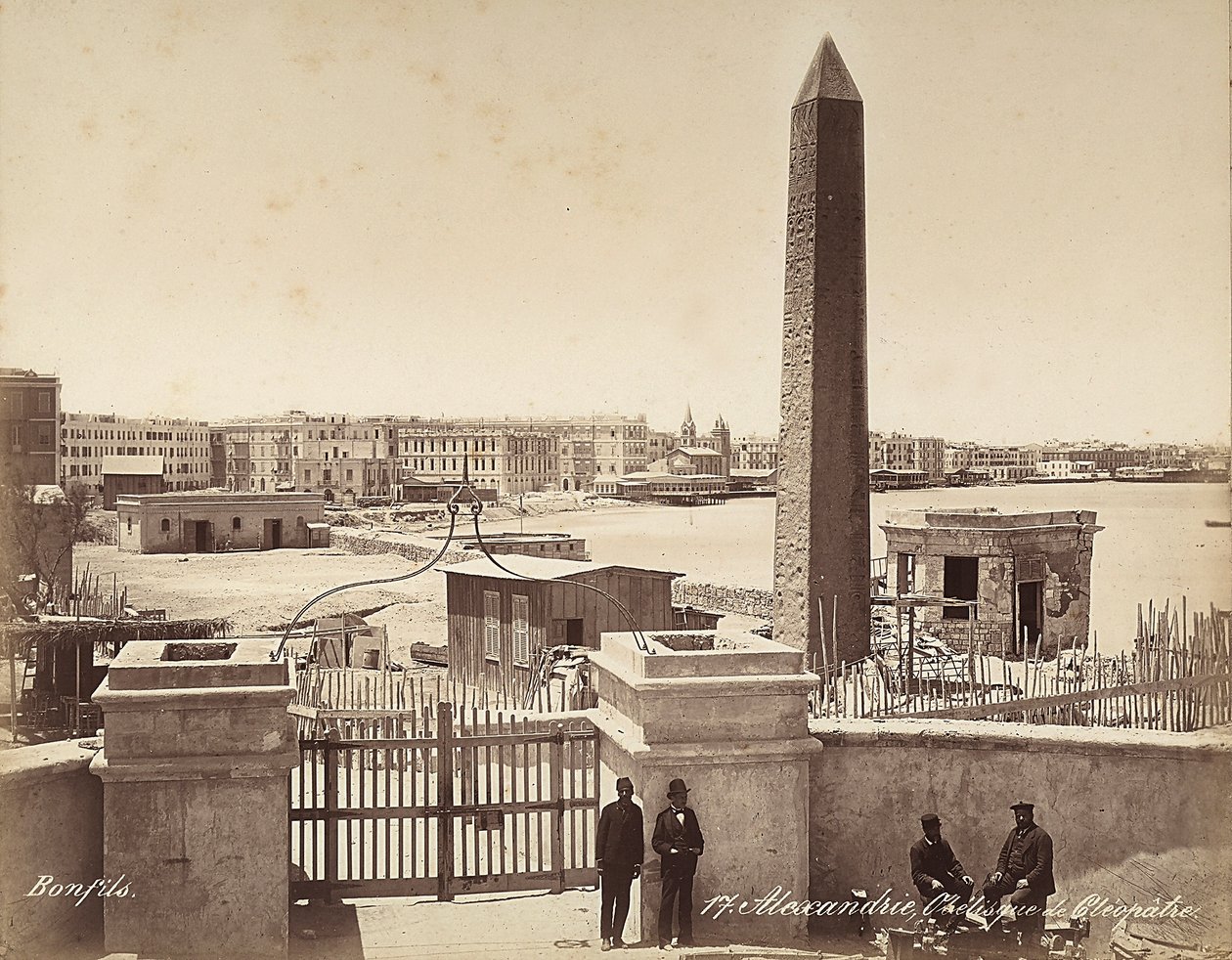 الإسكندرية ، مصر: مسلة كليوباترا ، مع أربعة رجال يقفون لالتقاط الصورة بواسطة فيليكس بونفيس