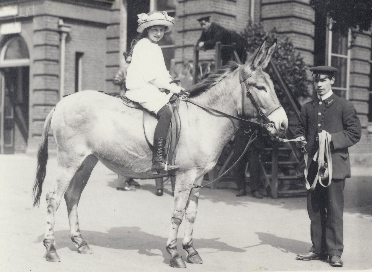سيدة شابة تركب مؤخرة يقودها حارس واحد بينما ينظر آخر إلى حديقة حيوان لندن في مايو 1914 بواسطة فريدريك وليام بوند