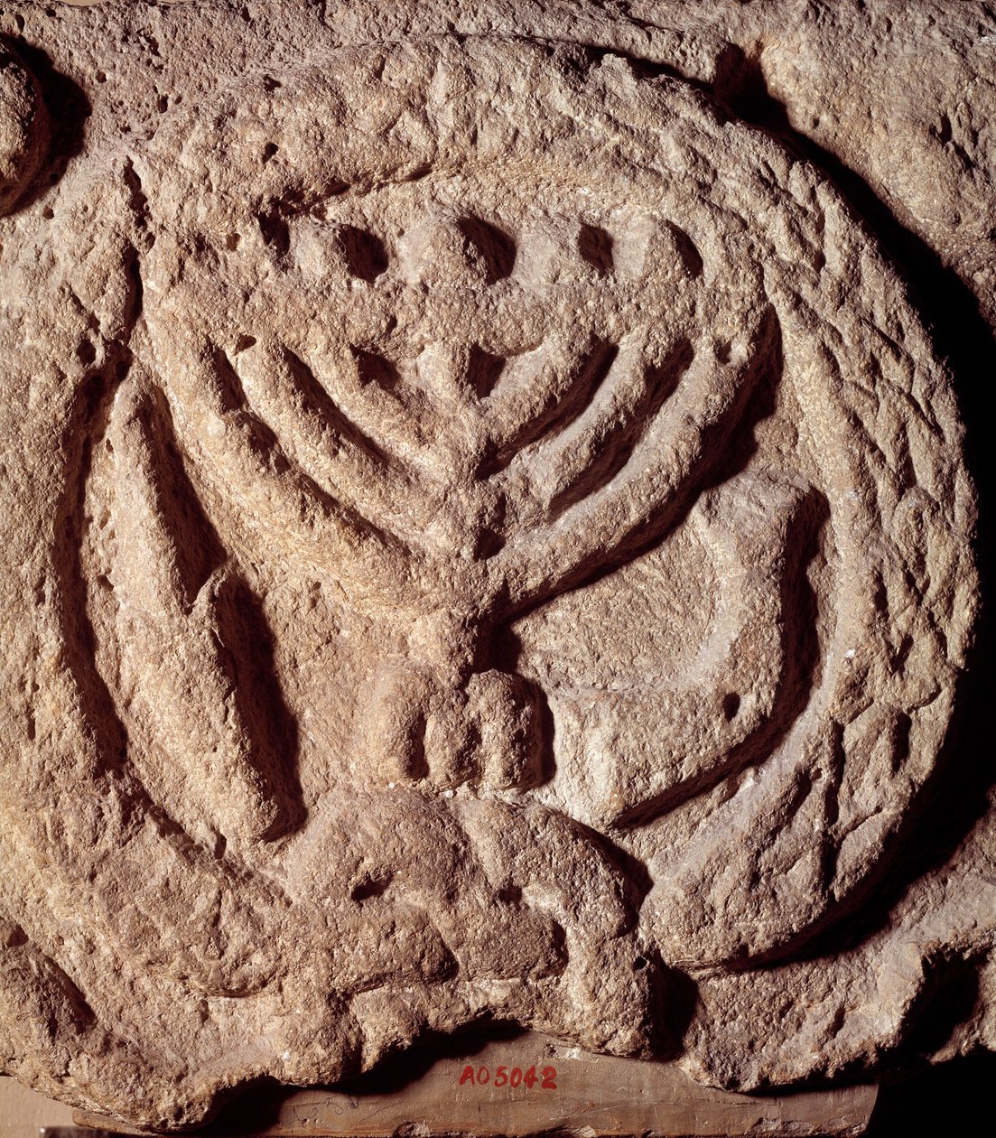 Judaism: architectural element in basalt of a synagogue decorated with a candlestick with seven branches (Menora or Menorah), palm and trumpet. From Transjordan. About 100 AD. Paris, Louvre Museum بواسطة المدرسة اليهودية