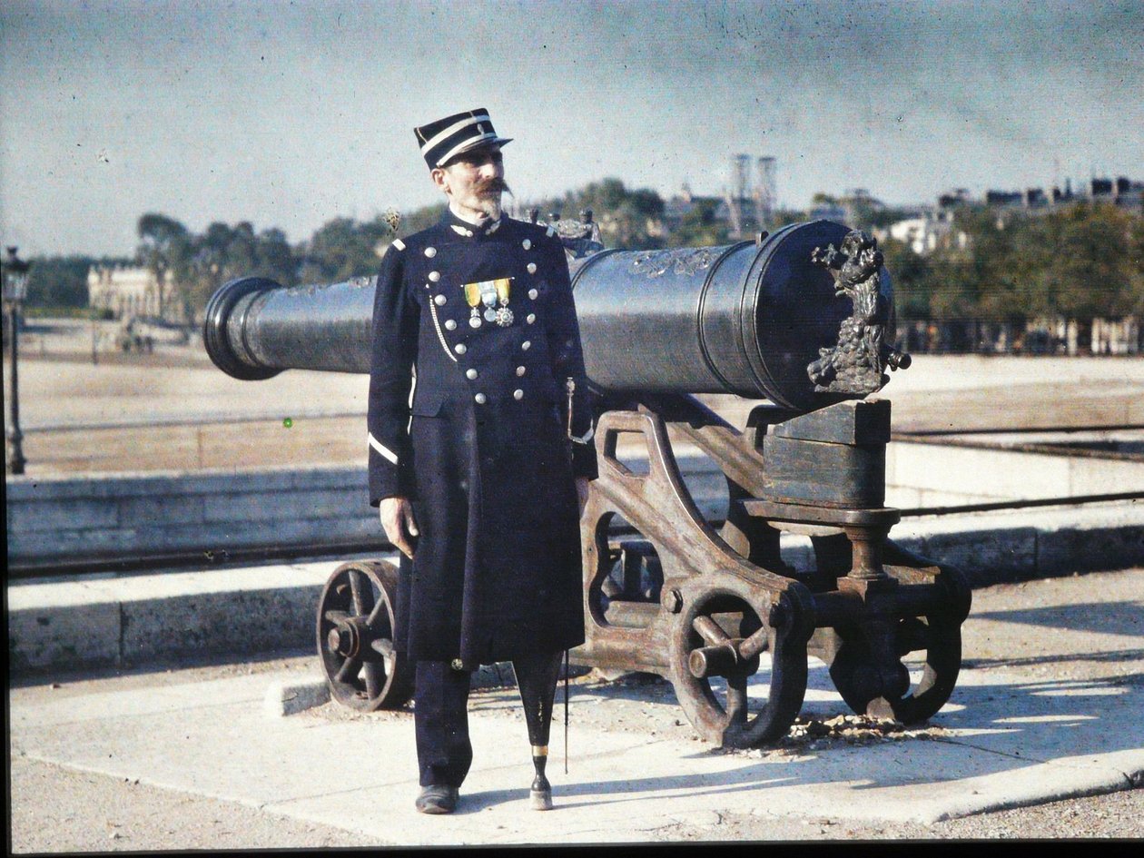 جندي يرتدي الزي العسكري ويحمل ثلاث ميداليات يقف بجانب مدفع في باريس ، 1918 (ذاتي اللون) بواسطة جول جيرفيه كورتيلمونت