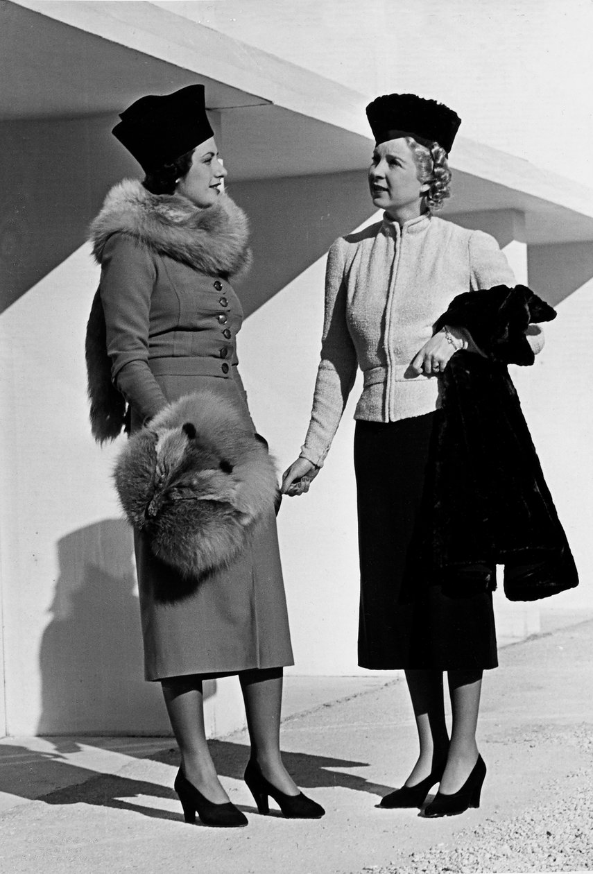 يقدم نموذجان ملابس نهارية تم إنشاؤها بواسطة دار الأزياء الراقية "فوماخ". ترتدي العارضة الموجودة على اليسار فستانًا مكملاً بسرقة الثعلب وفشل. يرتدي النموذج الموجود على اليمين بدلة تتكون من سترة قصيرة وتنورة. (ب / ث الصورة) بواسطة لويس بوجينو