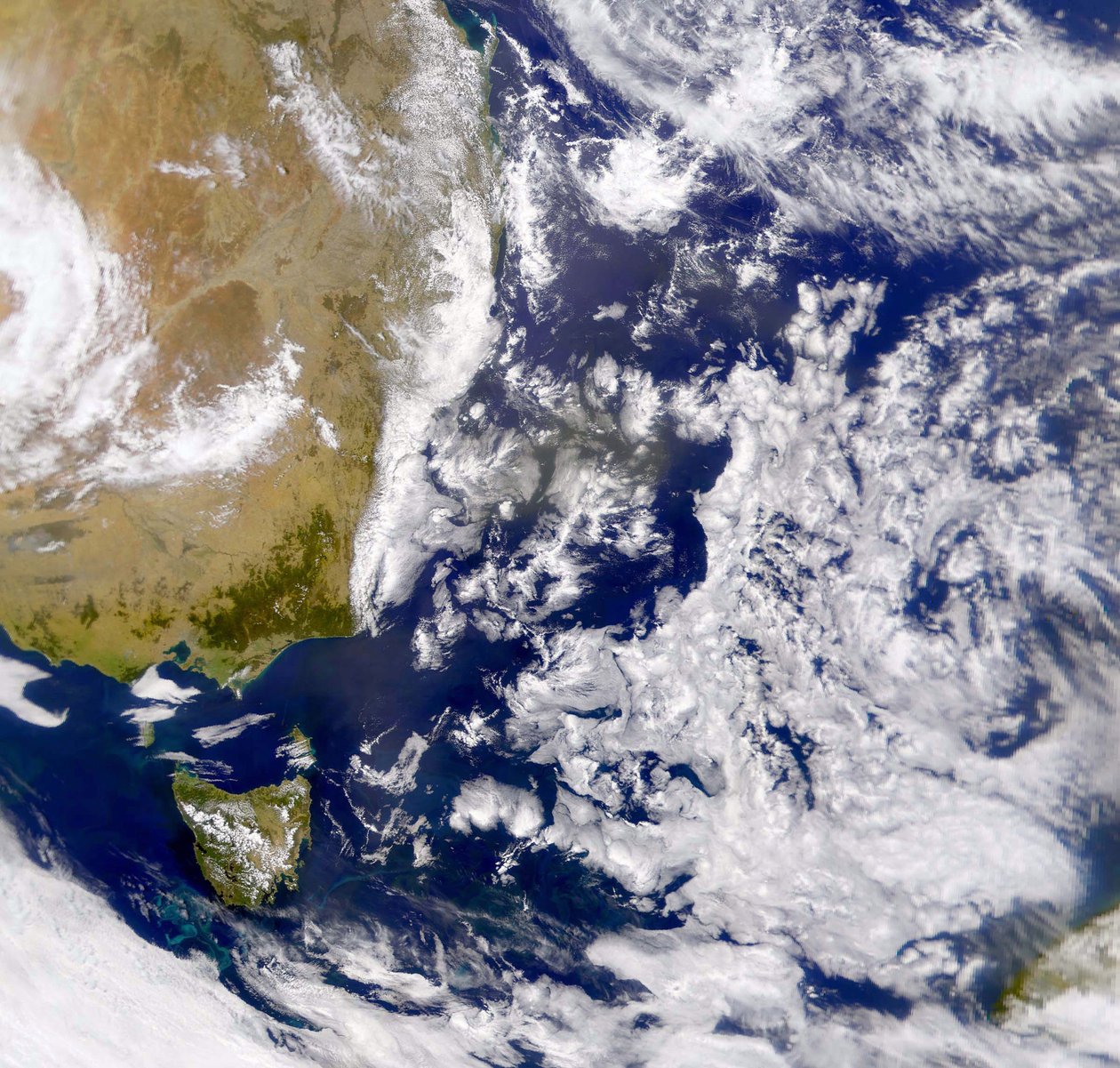 صورة ساتلية لبحر تاسمان مغطاة جزئيًا بالسحابة. على اليسار جزء من أستراليا تحته تسمانيا. وكالة ناسا. علم بواسطة الإدارة الوطنية للملاحة الجوية والفضاء الإدارة الوطنية للملاحة الجوية والفضاء