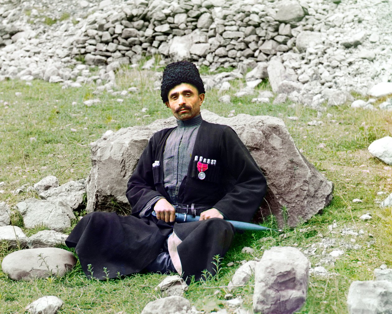 أنواع داغستاني - رجل مسلم سني يرتدي لباسًا تقليديًا وأغطية رأس ، مع خنجر مغلف على جانبه يجلس على الأرض ، الإمبراطورية الروسية ، بين عامي 1905 و 1915 بواسطة سيرجي بروكودين غورسكي