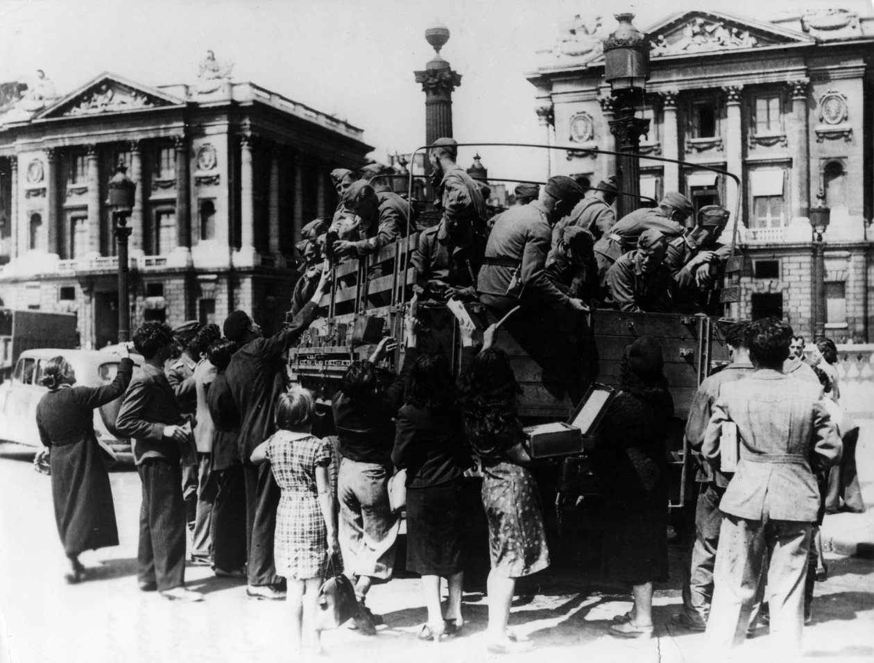 بائعو الشوارع الفرنسيون يقدمون هدايا تذكارية لشاحنة من الجنود الألمان ، باريس ، 27 يوليو 1940 بواسطة غير معروف