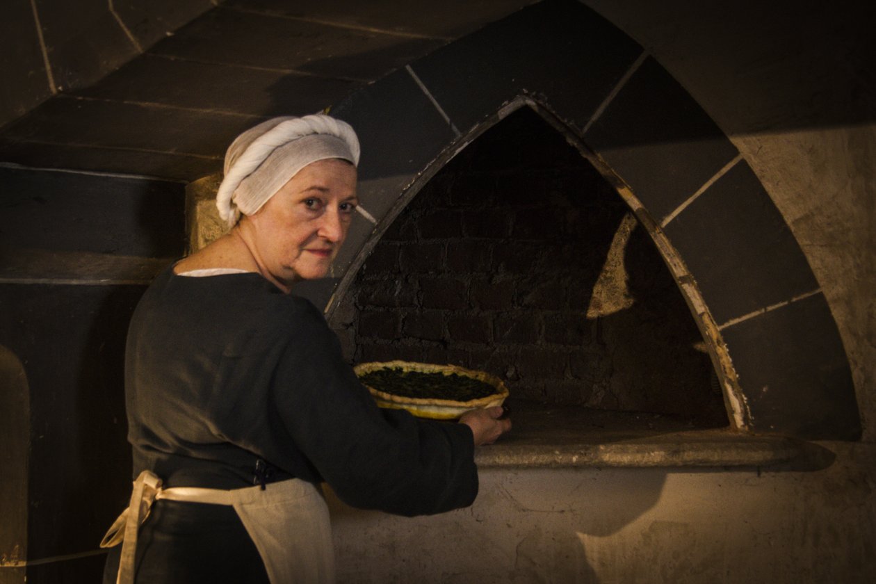Historical reenactment: Maid putting cake in oven of kitchen of castle بواسطة WG (بعد) ثاير