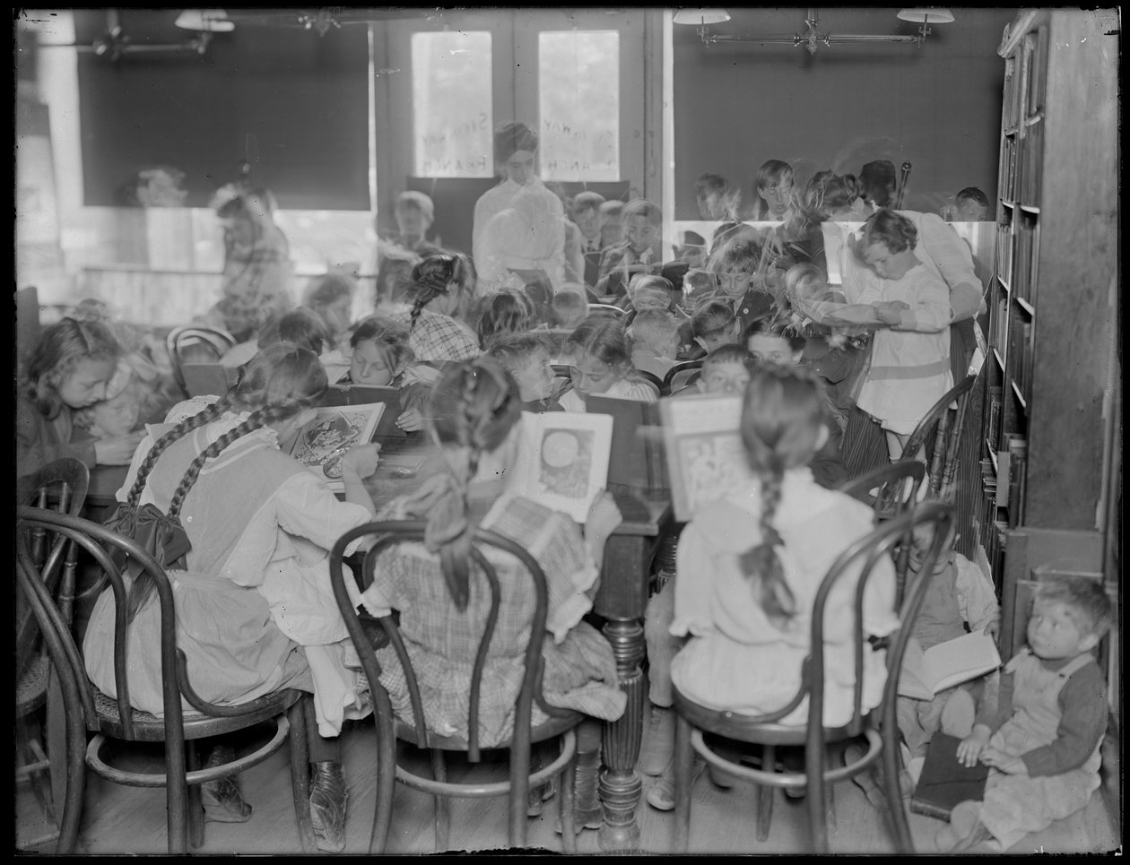 أطفال يقرؤون في غرفة القراءة في فرع مجهول من مكتبة Queens Borough العامة ، ج .1910. بواسطة وليام ديفيس هاسلر