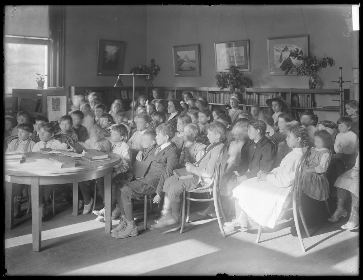 أطفال جالسون ، يستمعون في غرفة القراءة في فرع مجهول من مكتبة Queens Borough العامة ، ج .1910 بواسطة وليام ديفيس هاسلر