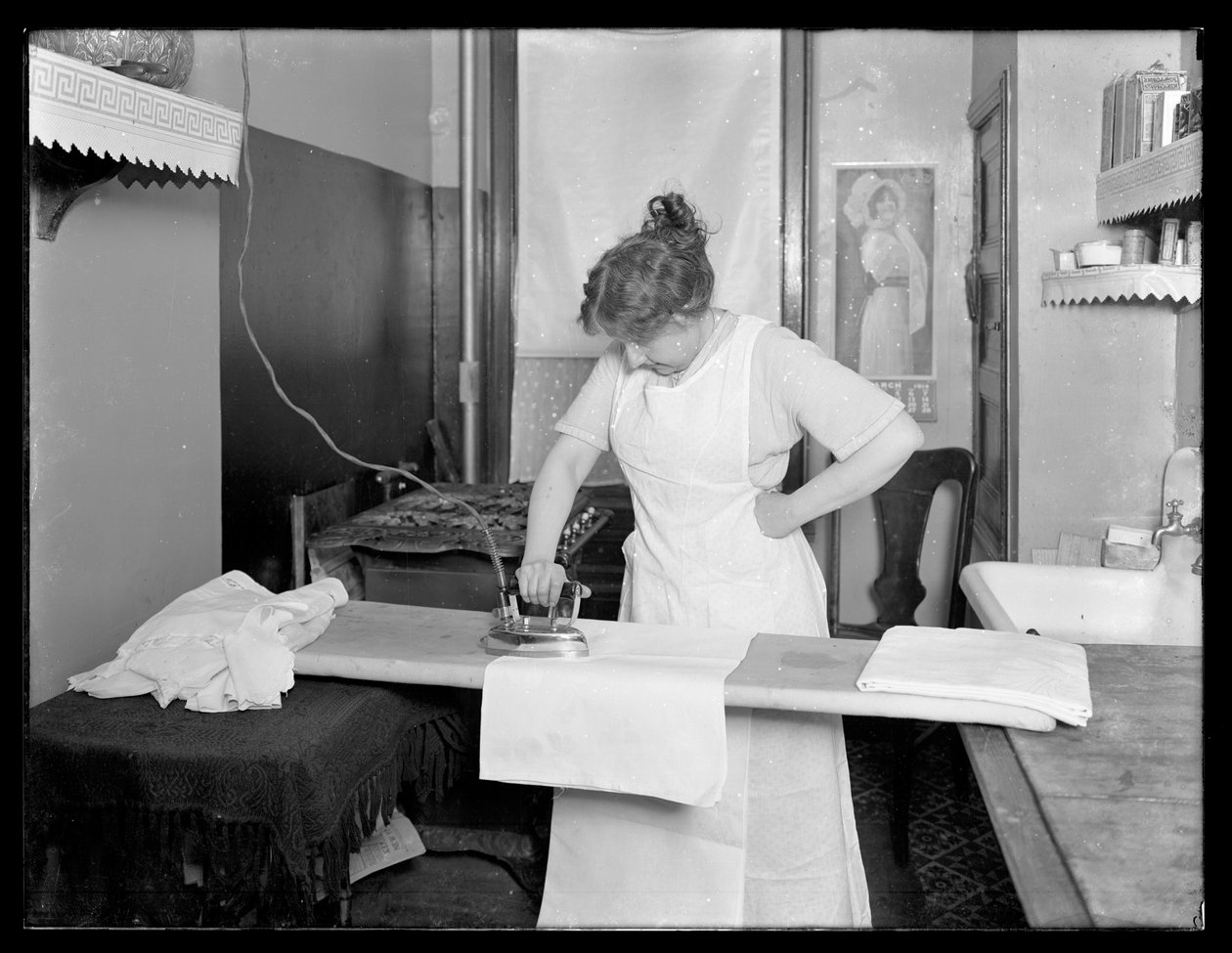 امرأة مجهولة الهوية توضح استخدام مكواة كهربائية ج .1913-14 بواسطة وليام ديفيس هاسلر