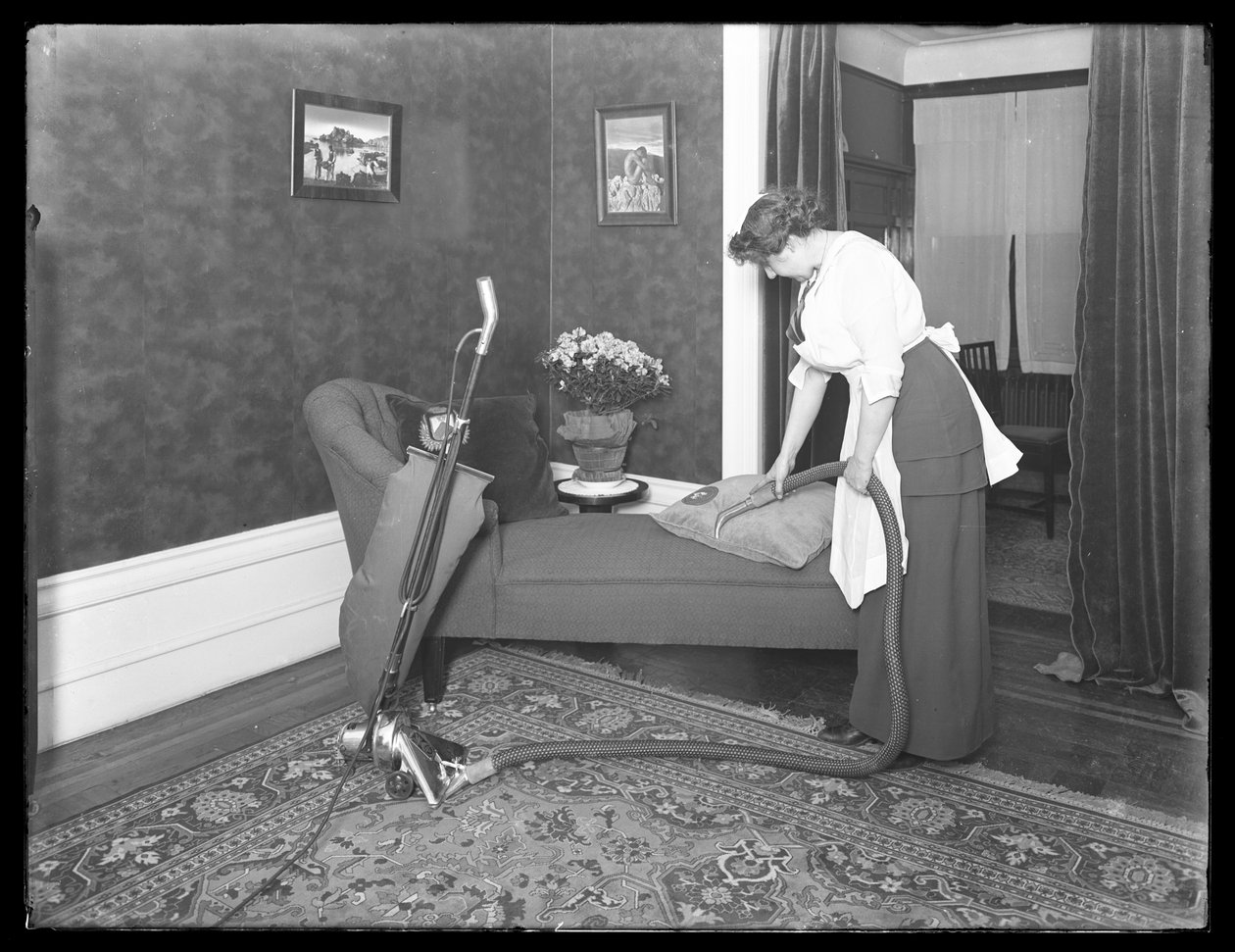 امرأة مجهولة الهوية توضح استخدام ملحق المفروشات في المكنسة الكهربائية Apex ، c.1913-14 بواسطة وليام ديفيس هاسلر