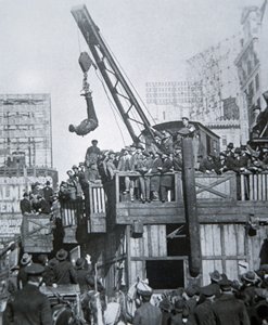 Houdini escaping from a strait-jacket while suspended from a crane in New York City (b/w photo) بواسطة مصور أمريكي