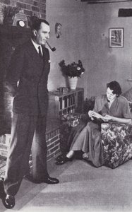 الزوجة تقرأ ، والزوج يدفئ ظهره ضد النار حوالي عام 1950 بواسطة مصور انجليزى