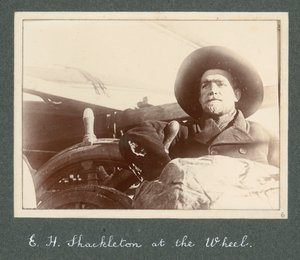 إي إتش شاكلتون يقف بجانب عجلة السفينة "ديسكفري" (1901) من ألبوم السير إرنست هنري شاكلتون بعنوان البعثة الوطنية للقطب الجنوبي (1901-1903) بواسطة إرنست هنري شاكلتون