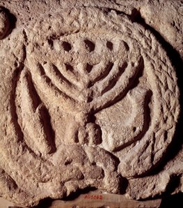 Judaism: architectural element in basalt of a synagogue decorated with a candlestick with seven branches (Menora or Menorah), palm and trumpet. From Transjordan. About 100 AD. Paris, Louvre Museum بواسطة المدرسة اليهودية