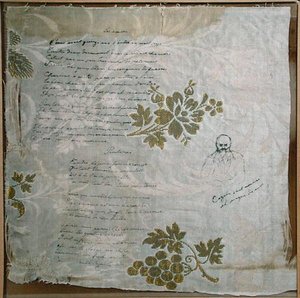 قطعة من مفرش المائدة كتب عليها فيرلين قصائده "Les Amies" و "Le Printemps" ، مع صورة لفيرلين لكازالز (قلم وحبر على القماش) بواسطة بول فيرلين