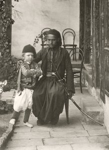 القواس العربي (الحرس العثماني) مع صبي صغير في حديقة منزل في منطقة يهودا بالقدس ، 1867