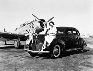 كاليفورنيا: 1939 امرأتان تجلسان على مصدات سيارة لينكولن زفير سيدان عام 1939 في مطار مع طائرة ذات محرك واحد متوقفة خلفهما (صورة أبيض وأسود) بواسطة غير معروف