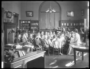 أطفال يستمعون إلى امرأة في غرفة القراءة في فرع مجهول من مكتبة Queens Borough العامة ، ج .1910 بواسطة وليام ديفيس هاسلر