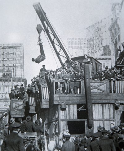 Houdini escaping from a strait-jacket while suspended from a crane in New York City (b/w photo) بواسطة مصور أمريكي