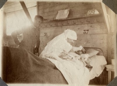 الحرب العالمية الأولى 1914-1918: ممرضة في بلوزة تحلق الجندي (جروح الحرب الفرنسية ملقاة على سرير) ، في كوفيل ، مانش ، نورماندي السفلى (نورماندي السفلى) ، فرنسا. صورة مجهولة ، يوليو 1917. مجموعة خاصة ، ستيلا. بواسطة مجهول مجهول