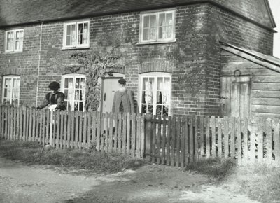مشهد ريفي في منطقة Wandsworth مع زوجين مسنين في حديقة عقار على طراز الكوخ ، لندن ، 1895 بواسطة مصور انجليزى