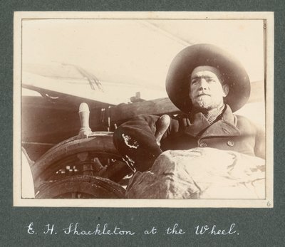 إي إتش شاكلتون يقف بجانب عجلة السفينة "ديسكفري" (1901) من ألبوم السير إرنست هنري شاكلتون بعنوان البعثة الوطنية للقطب الجنوبي (1901-1903) بواسطة إرنست هنري شاكلتون