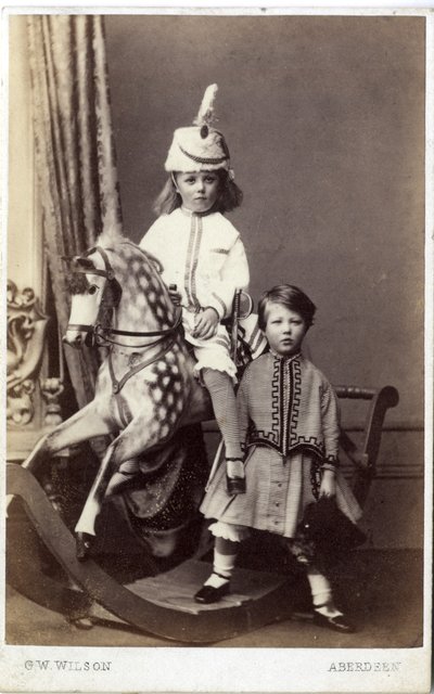 فتاة صغيرة ترتدي قبعة على حصان هزاز مع فتاة أخرى تقف ، 1860s (طبعة زلال) بواسطة جورج واشنطن ويلسون