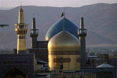 القبة الذهبية بالكامل ومئذنة ضريح الإمام رضا ، الإمام الشيعي الثامن ، وراءها مسجد تيمور شاد خلف بواسطة مدرسة إسلامية