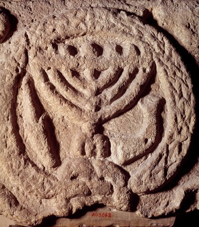 Judaism: architectural element in basalt of a synagogue decorated with a candlestick with seven branches (Menora or Menorah), palm and trumpet. From Transjordan. About 100 AD. Paris, Louvre Museum بواسطة المدرسة اليهودية