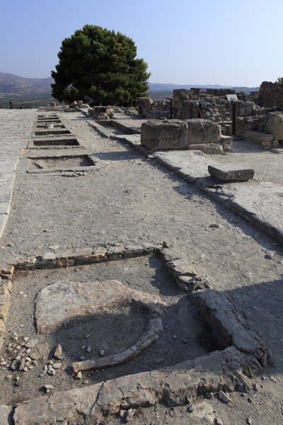 موقع مينوان الأثري لفيستوس. منظر عام لأضرحة الجناح الغربي على طول الفناء المركزي من الجناح الشمالي. كان هناك نوعان من المزارات: "ضريح مقعد" و "حوض محايد". كان "ضريح البدلاء" عبارة عن غرفة صغيرة مستطيلة الشكل ذات مساحة منخفضة بواسطة مينوان