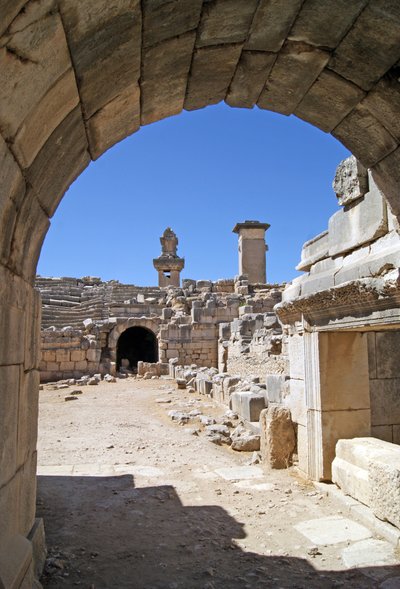 منظر من خلال المدخل المقبب لمسرح Xanthos في حفرة الأوركسترا ، يُظهر العمود وقبر Harpy ، Xanthos ، تركيا (صورة) بواسطة رواية
