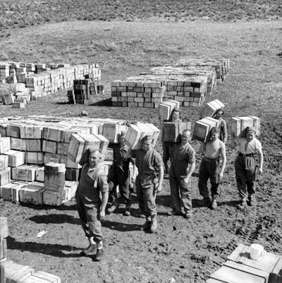 مكب للحصص التموينية ورجال يحملون المزيد من الإمدادات إليه ، مارس 1943 (شريحة فانوس) بواسطة غير معروف
