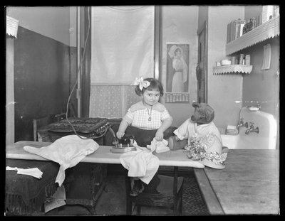 طفلة مجهولة الهوية توضح استخدام مكواة كهربائية ، حوالي 1913-14 بواسطة وليام ديفيس هاسلر