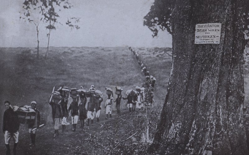Line of men carrying goods from the equator to Selfridges, London (b/w photo) بواسطة مصور انجليزى